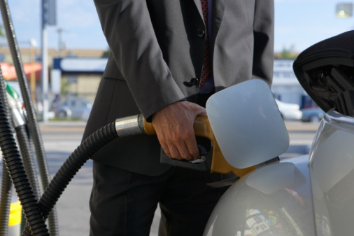Businessman filling gas into car, close up