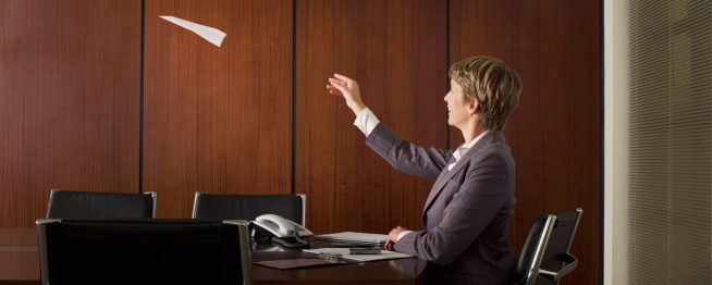 Businesswoman throwing paper airplane